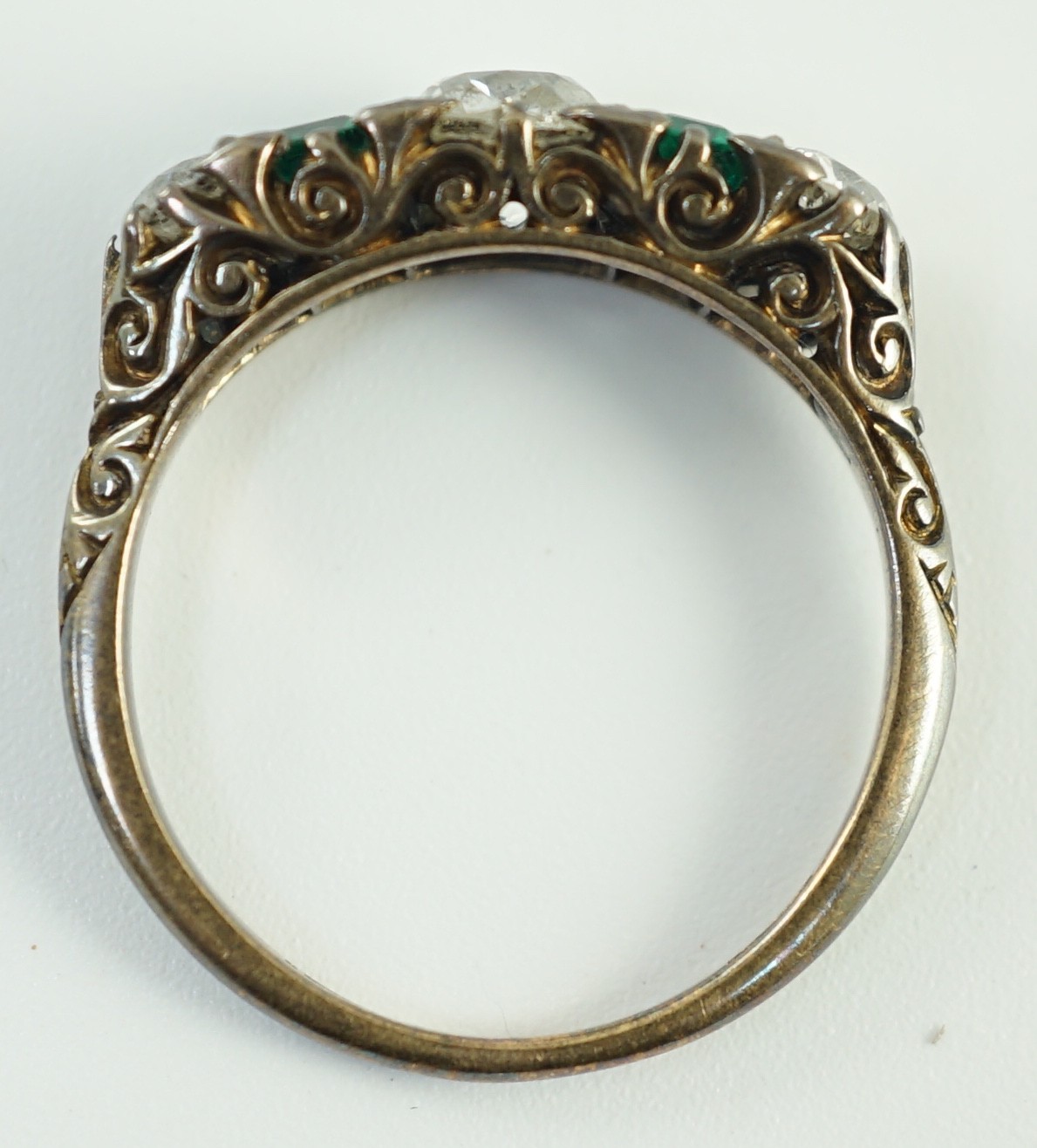 An early 20th century 18ct gold, three stone diamond and two stone emerald set half hoop ring